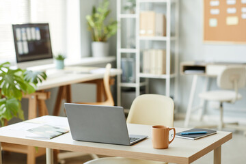Background image of workplace design with open laptop on table in minimal office interior, white color dominant