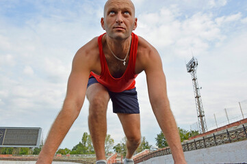 bald male athlete doing push-ups on the rubber floor at the stadium. outdoor training. active lifestyle and sports concept