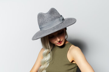 Studio portrait of young blonde girl wearing grey hat on white background.