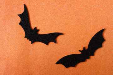 Halloween paper bat - top view flat lay. Orange paper background with black bats. Halloween and decoration concept - black paper bats flying on orange background. High quality photo.