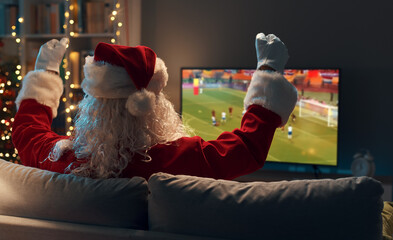 Happy Santa Claus watching football on TV