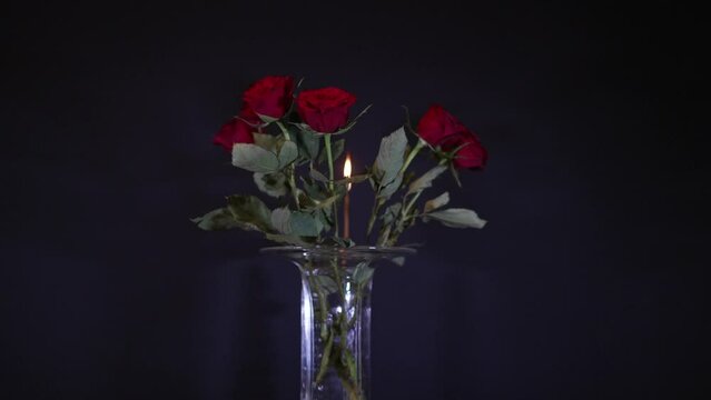 Bunch of beautiful red roses in a glass vase with incense burning incense stick in the background. Slow motion movie shot October 12th, 2022, Zurich, Switzerland.