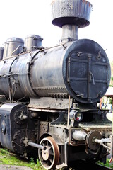 Historic railway. The front part of a steam locomotive. A fragment of the boiler, wheels, pistons, lantern and bumper are visible.