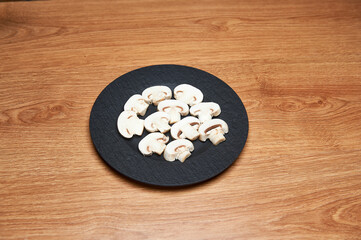 Obraz na płótnie Canvas sliced mushrooms on black plate