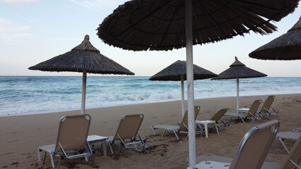 Aerial view of rows of cane umbrellas and sunbeds on a sandy Mediterranean beach
