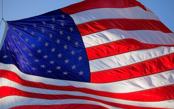 american flag blowing across the frame with blue sky background 