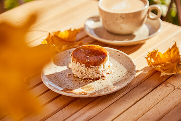 Aesthetic autumn healthy carrot dessert with agave syrup. Cake with cup of coffee under hard shadows outside. Healthy breakfast
