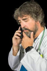 doctor dressed in the blue surgical suit and white coat consulting a mobile phone