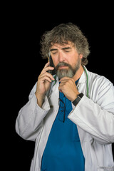 doctor dressed in the blue surgical suit and white coat consulting a mobile phone