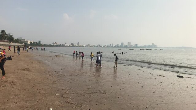 Mumbai, India, November 2019 - A group of people standing on top of a sandy beach