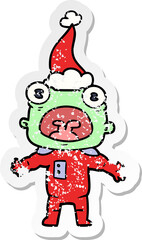 hand drawn distressed sticker cartoon of a weird alien communicating wearing santa hat