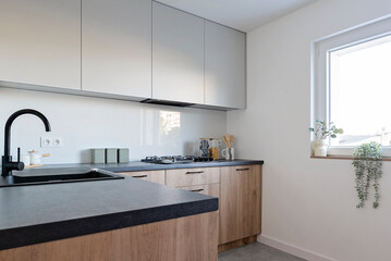 Kitchen interior with wooden cabinets and sink with tap and window. Minimal room in apartment.