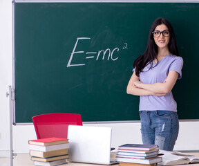 Young female teacher student in front of green board