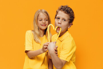 cute, happy children brother and sister, stand in bright clothes and put their candies to each...