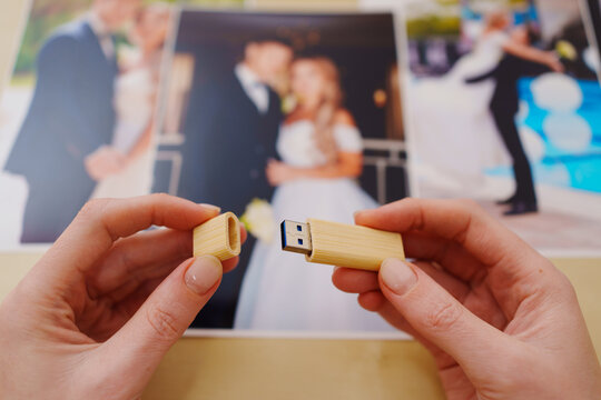selective focus. printed wedding photos, wooden box and hands with flash drive
