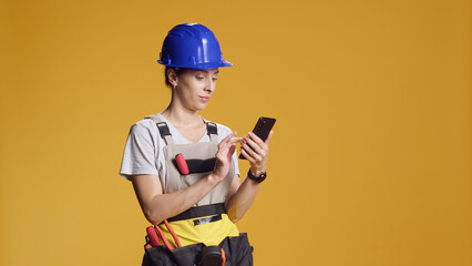 Portrait of woman engineer using smartphone to browse internet and find refurbishment inspiration. Confident person with atypical job feeling empowered by deconstruction work.