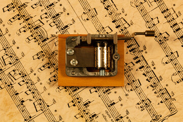 Music box and notes. Souvenir Music box on the background of old notes. Hand organ for classical and modern melody. Retro cylindrical mechanism with hand-cranked movements on wooden stand. Top view