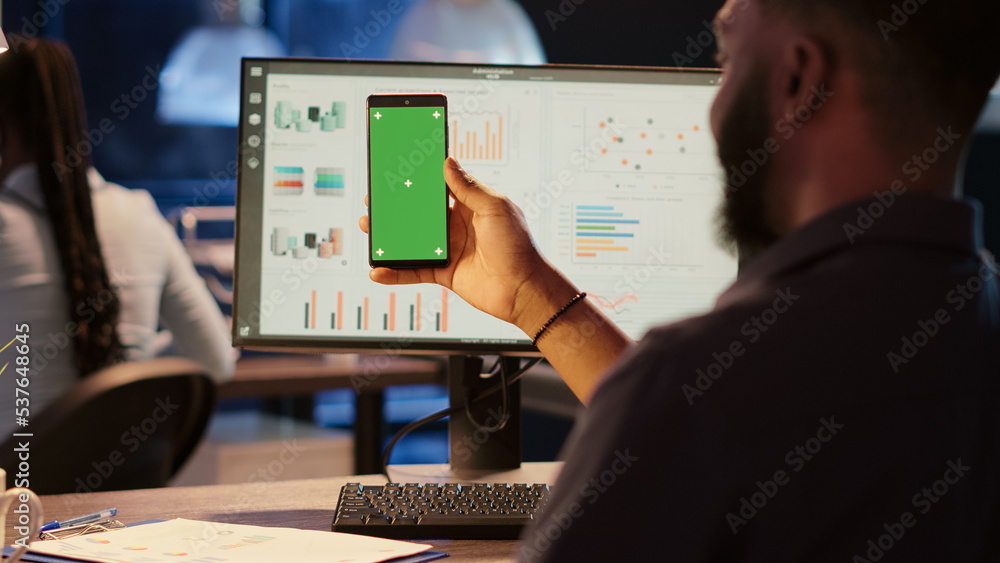 Poster business man looking at greenscreen display on mobile phone, working in office at night. using isola