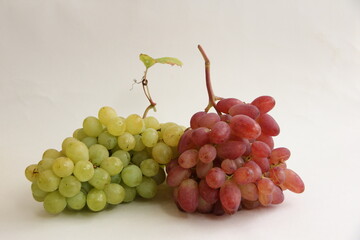 a bunch of red grapes and a bunch of green grapes on a white background