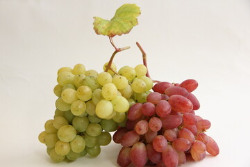 a bunch of red grapes and a bunch of green grapes on a white background