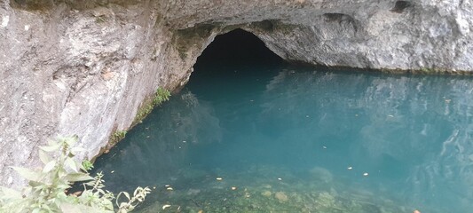 Beautiful flowing blue water under a stone leading into a cave