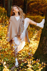 A fantastic woman in the autumn forest on the background of yellow cast threw her leg on a tree. Practically vertical twine.