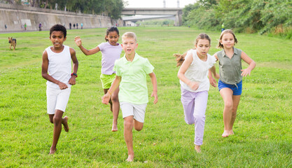 Group of laughing children having fun together outdoors running