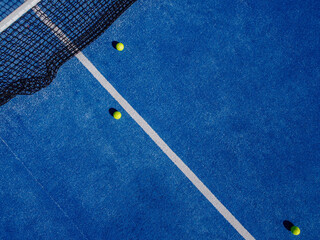 Drone aerial view of three balls in a blue paddle tennis court. Racket sports
