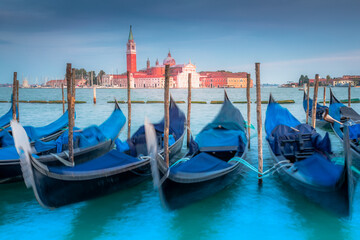 Fototapeta na wymiar Gondole docked by wooden mooring poles in grand canal, Ethereal Venice, Italy