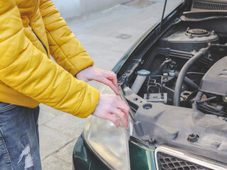 A young caucasian guy in a yellow jacket inspects the internal breakdown of the front headlight