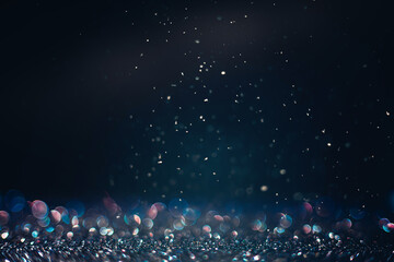 Defocused black glitter texture with iridescent bokeh and snow in the dark