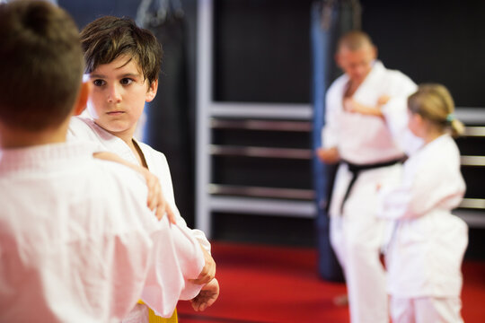 Focused preteen boys practicing new karate moves in pairs at sport gym