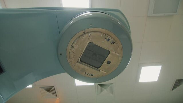 Builder puts plaster on putty knife to decorate wall and linear particle accelerator in hospital combined shot. Medical center