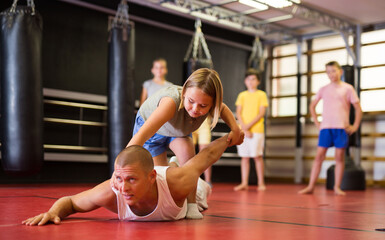 Concentrated preteen girl practicing effective self defence techniques with coach in training room
