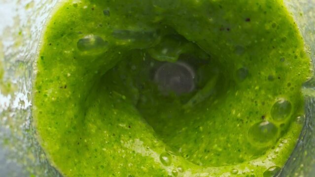 Green vegetable blend mixing in blender close up top view. Preparing smoothie.