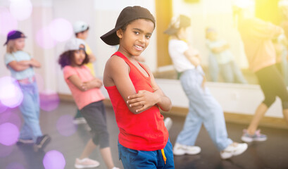 Portrait of confident tween african boy hip hop dancer posing during group dance class ..