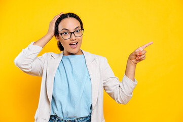 Excited gorgeous confident stylish successful brazilian or hispanic young woman, pointing her finger aside up on a mock-up copy-space, looks at camera in amazement, stand on isolated orange background