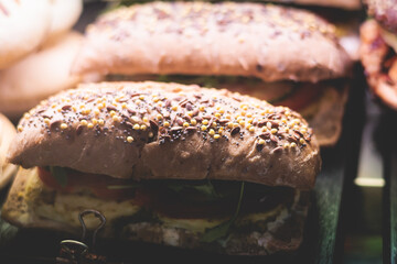 Beautifully decorated catering banquet table on event with different food snacks and appetizers setting with bagel and sandwiches, triange, baguette club submarine sandwich, on a wooden plate
