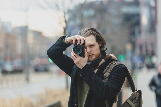 stylish guy in scarf and coat hold a photo camera at street of Wroclaw, Poland