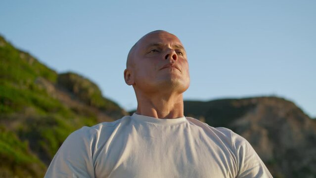 Portrait man breathing meditating at mountain sky. Zen muscular guy relaxing