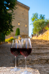Glass of red dry wine and ruins of medieval castle of Châteauneuf-du-Pape ancient wine making village in France