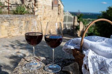 Glass of red dry wine and ruins of medieval castle of Châteauneuf-du-Pape ancient wine making village in France