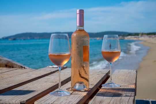 Glasses And Bottle Of Cold Rose Wine From Provence Served Outdoor On Wooden Yacht Pier With View On Blue Water And White Sandy Beach Plage De Pampelonne Near Saint-Tropez, France