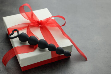Black anal beads and gift box on grey table, space for text. Sex toy