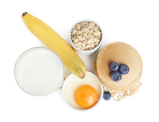 Tasty oatmeal pancakes and ingredients on white background, top view