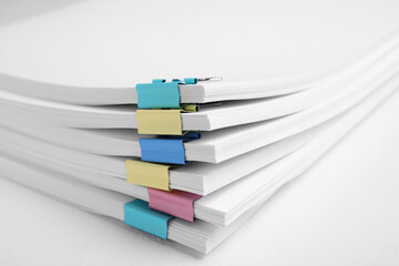 Many sheets of paper with colorful clips on white background, closeup
