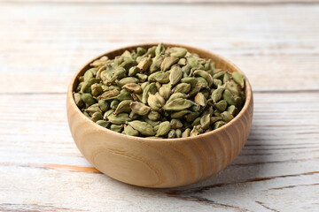 Bowl with dry cardamom on wooden table