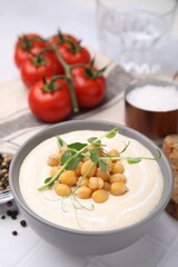 Tasty chickpea soup in bowl on white tiled table