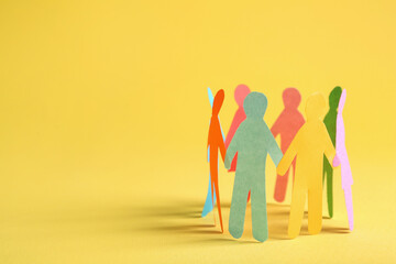 Many different paper human figures standing in circle on yellow background, space for text....
