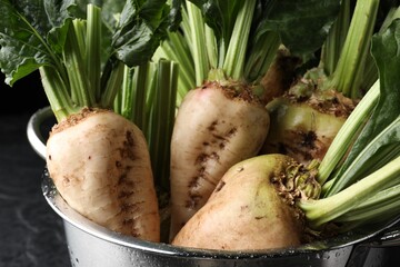 Colander with fresh sugar beets on black table, closeup